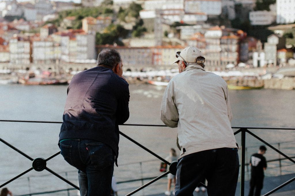 Two men leaning on a railing enjoying the view in Porto, Portugal.